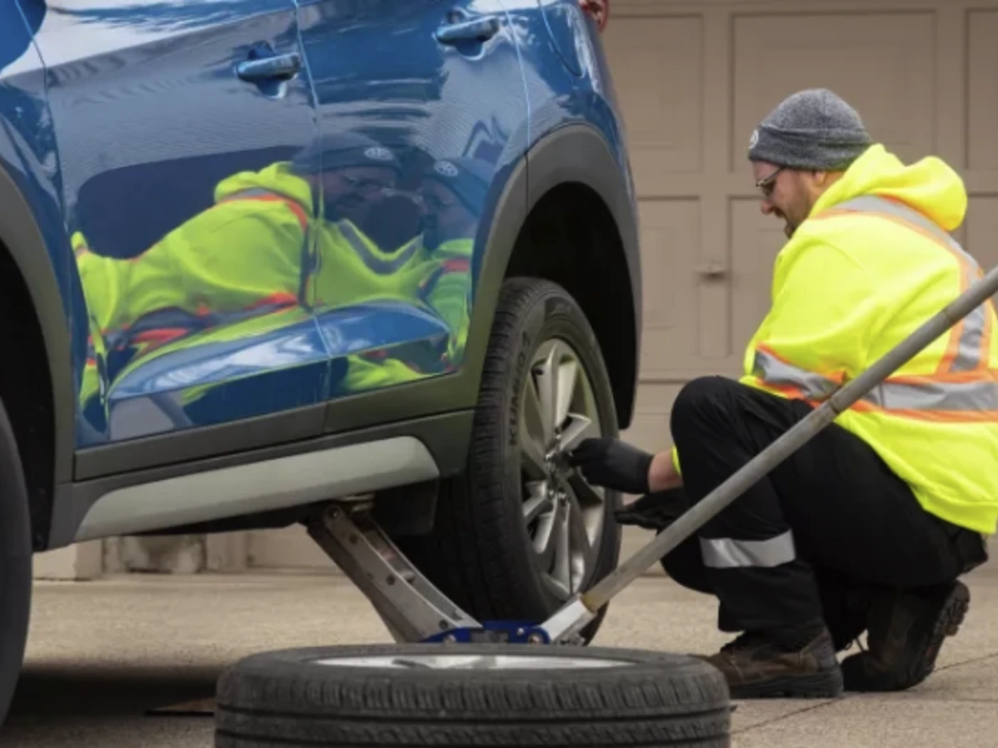 Professional tire change service technician replacing flat tire on roadside in San Diego